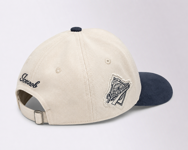 An off-white cotton baseball cap with a dark navy blue visor, featuring embroidered 'Swoonk' on the side and a 'Kreepsville' patch on the front, set against a light gray background.