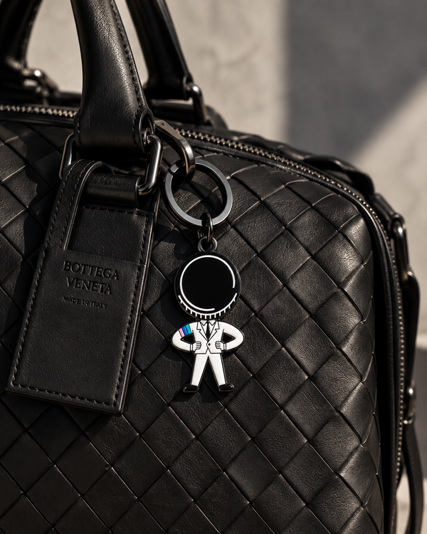 ICESNOB Mr. Puck keychain hanging from a black woven Bottega Veneta leather bag.